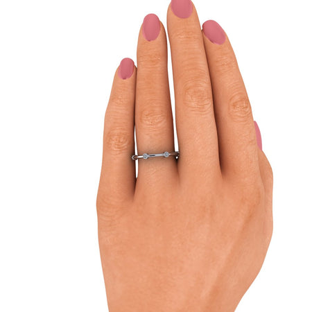 Minimalist diamond band ring on hand with pink manicured nails, white background