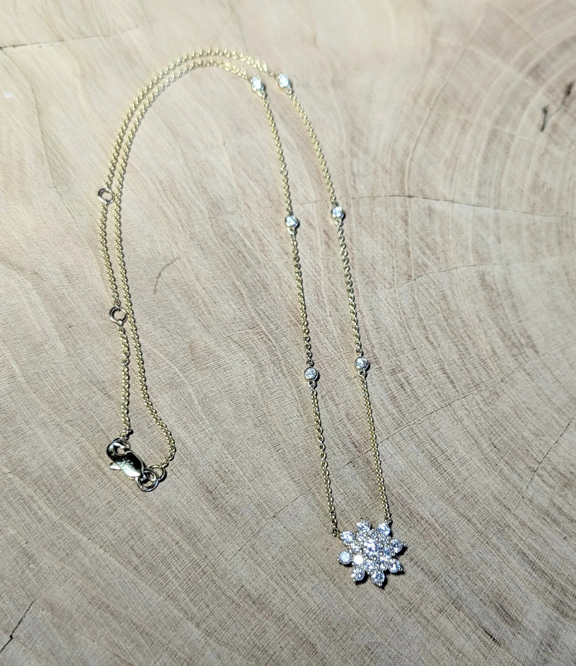 Gold chain necklace with diamond snowflake pendant on wood background