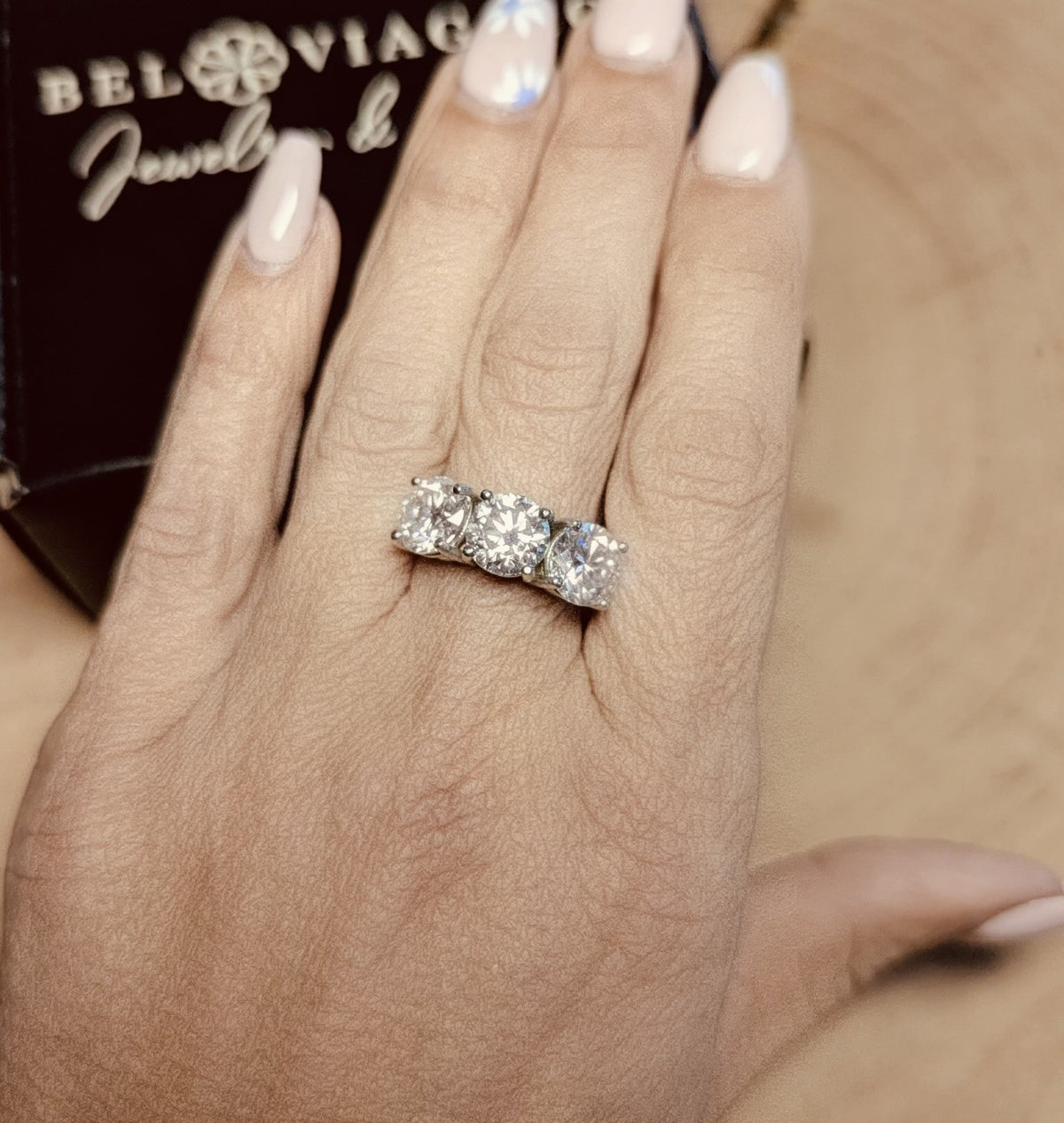 Three-stone diamond engagement ring on hand, custom jewelry, white gold setting