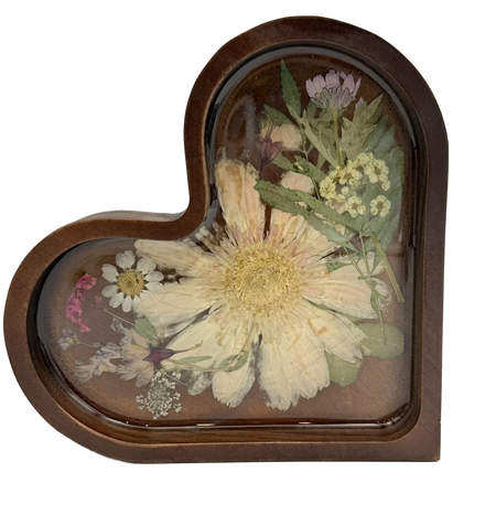 Heart-shaped resin keepsake with pressed dried flowers and greenery on a wood base