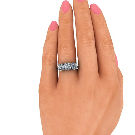 Hand with pink nails wearing a five-stone diamond engagement ring on white background