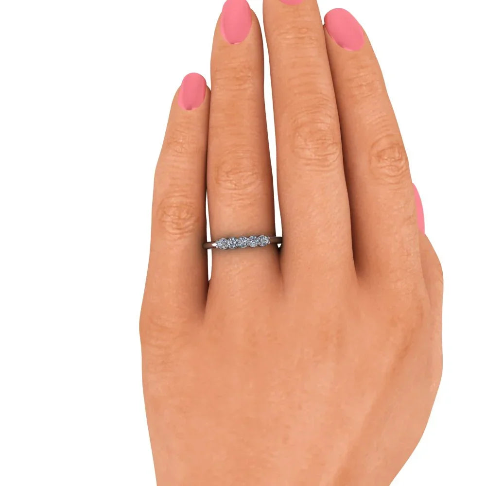 Hand with pink nails wearing a delicate diamond wedding band on ring finger