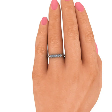 Hand with pink nails wearing a delicate diamond wedding band on ring finger