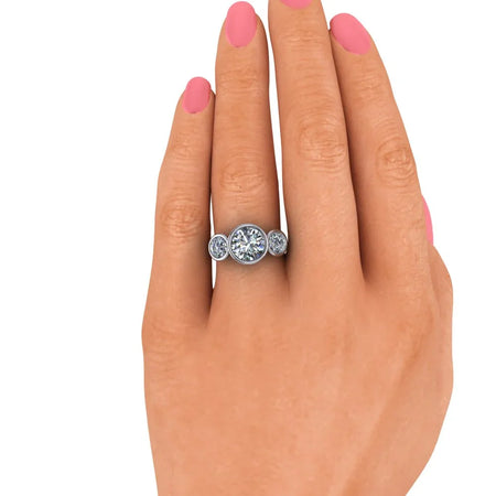 three-stone diamond engagement ring on hand with pink nails