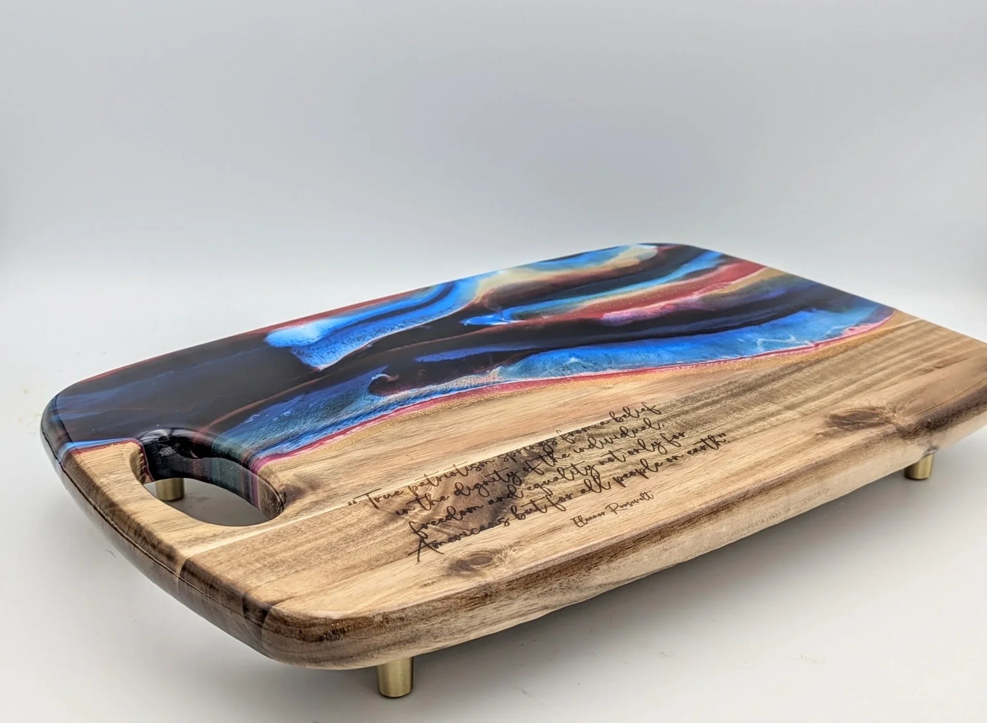 Handcrafted wood and resin serving board with engraved quote, blue and red swirl design, gold feet