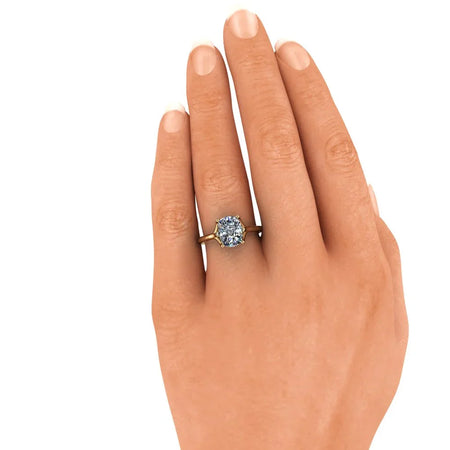 Gold solitaire engagement ring with a round diamond on a woman's hand
