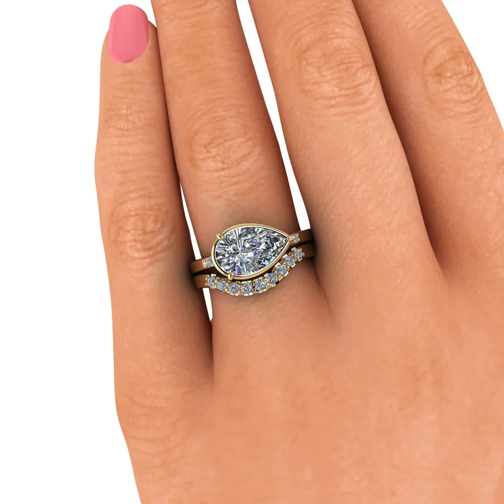 Pear-shaped diamond engagement ring set with gold bands and accent diamonds on hand