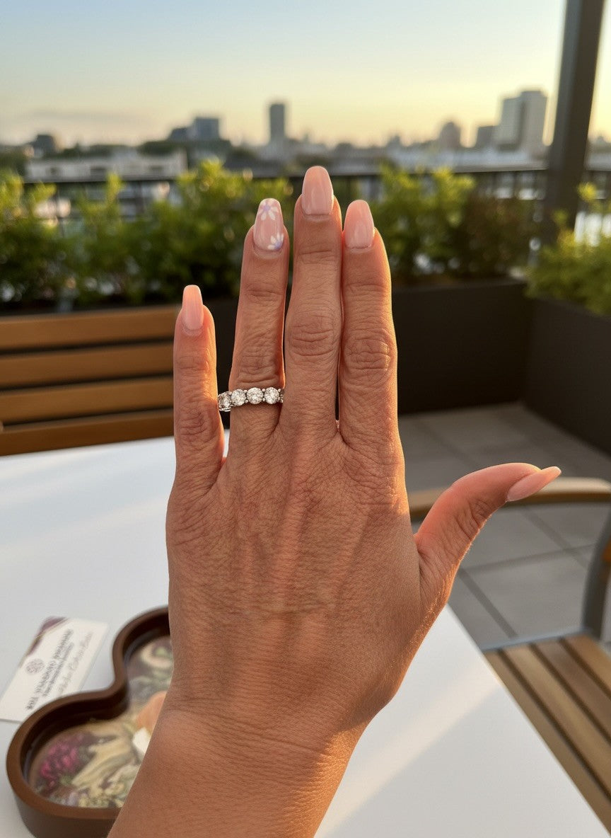 Hand with diamond engagement ring and manicured nails outdoors at sunset