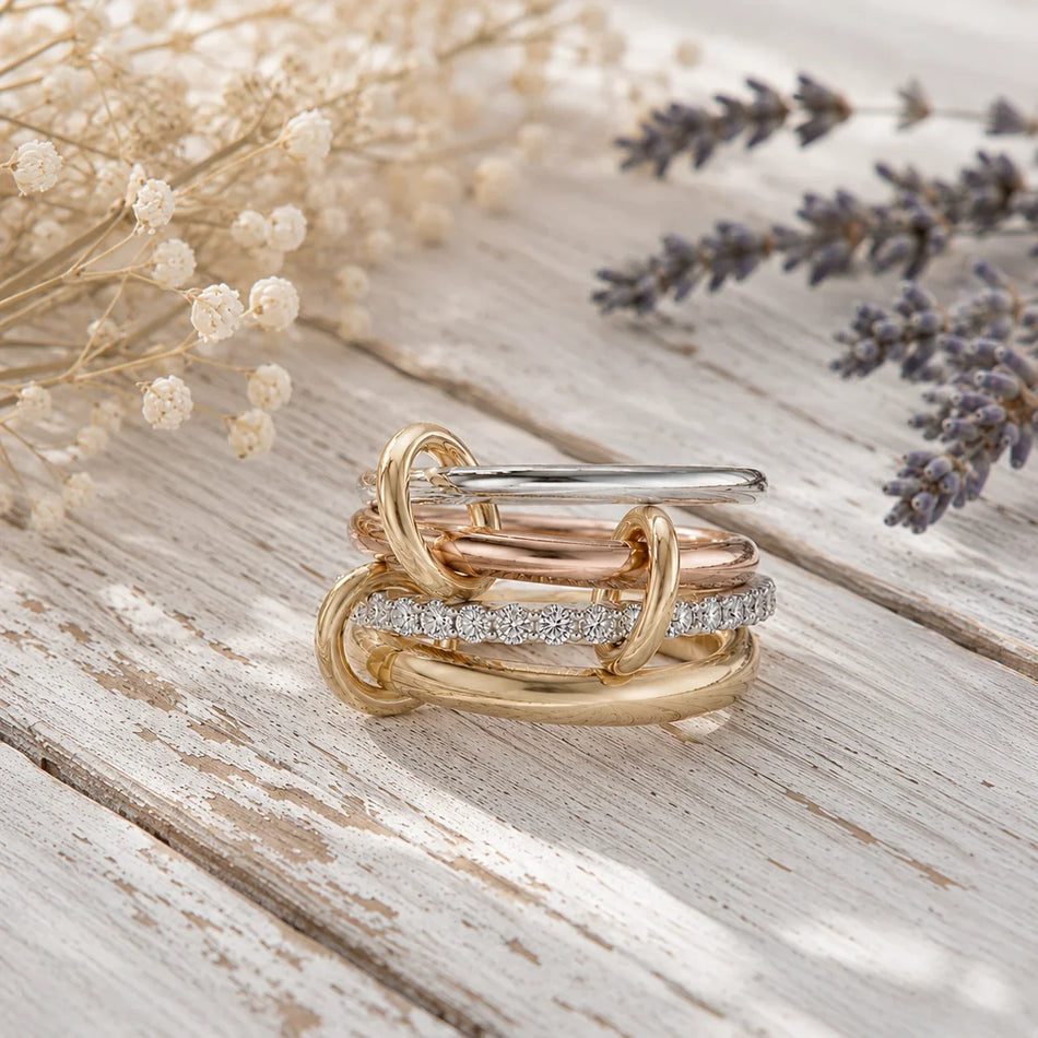 Stacked gold, rose gold, and diamond wedding bands on rustic wood with dried flowers