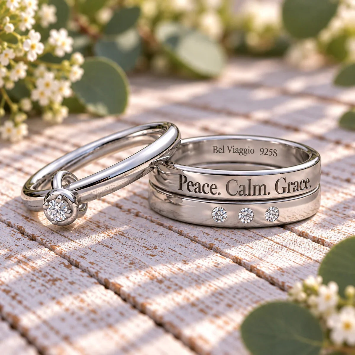 Two custom silver bands on a wooden surface, one with diamonds and 'Peace. Calm. Grace.' engraving.