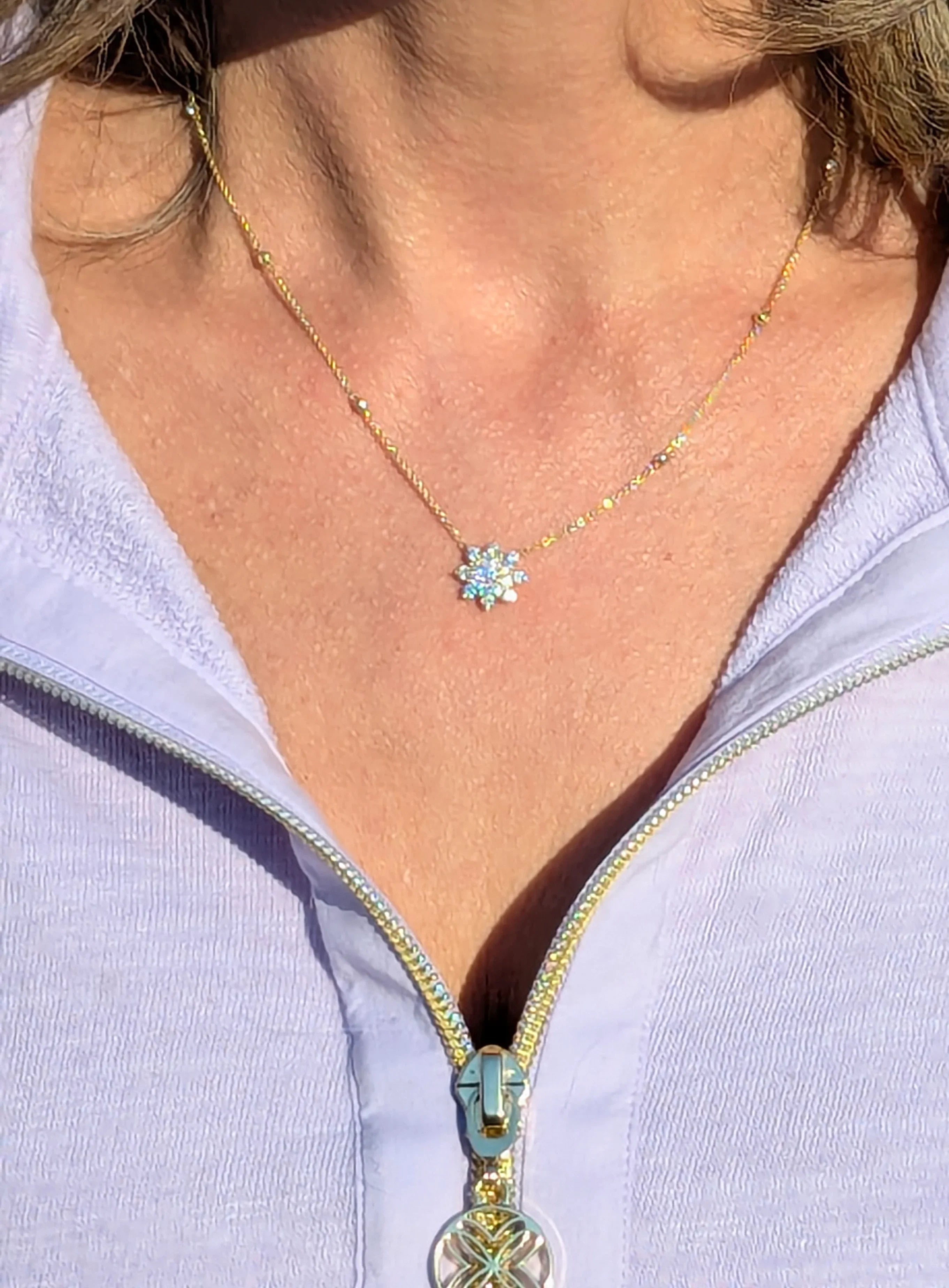 Gold necklace with sparkling flower-shaped diamond pendant on woman's neck