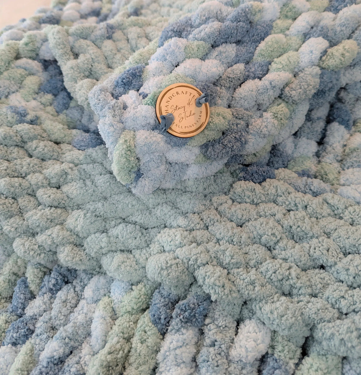 Handcrafted chunky knit pastel blue blanket with wooden tag detail