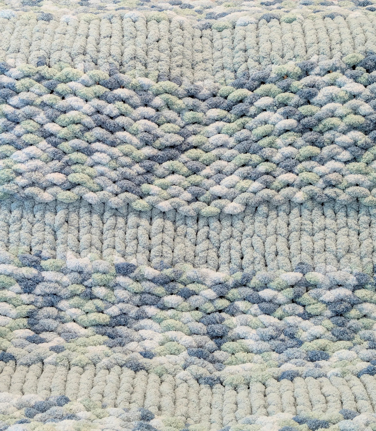 Close-up of textured knitted fabric with blue, white, and gray yarn pattern
