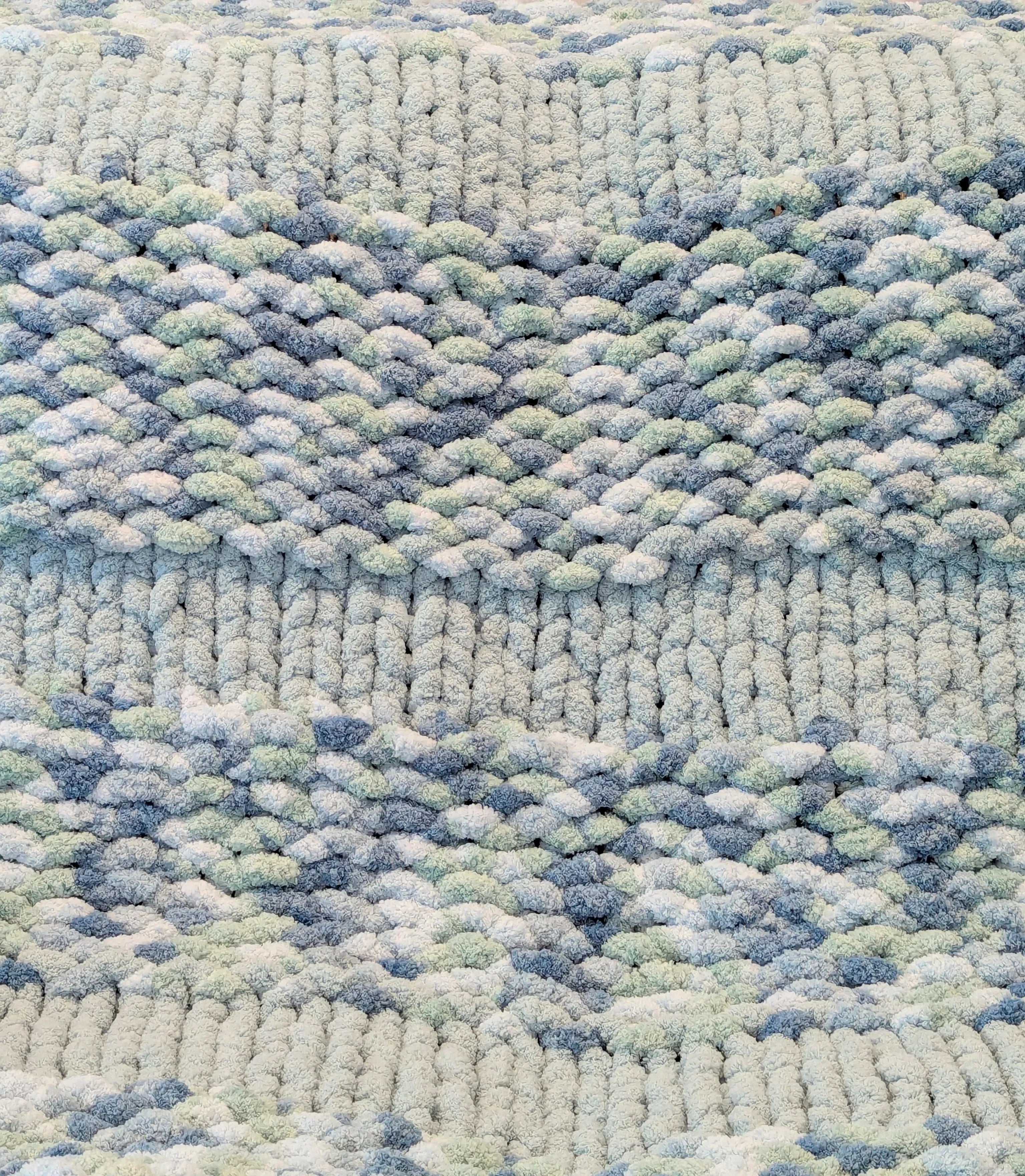 Close-up of textured knitted fabric with blue, white, and gray yarn pattern