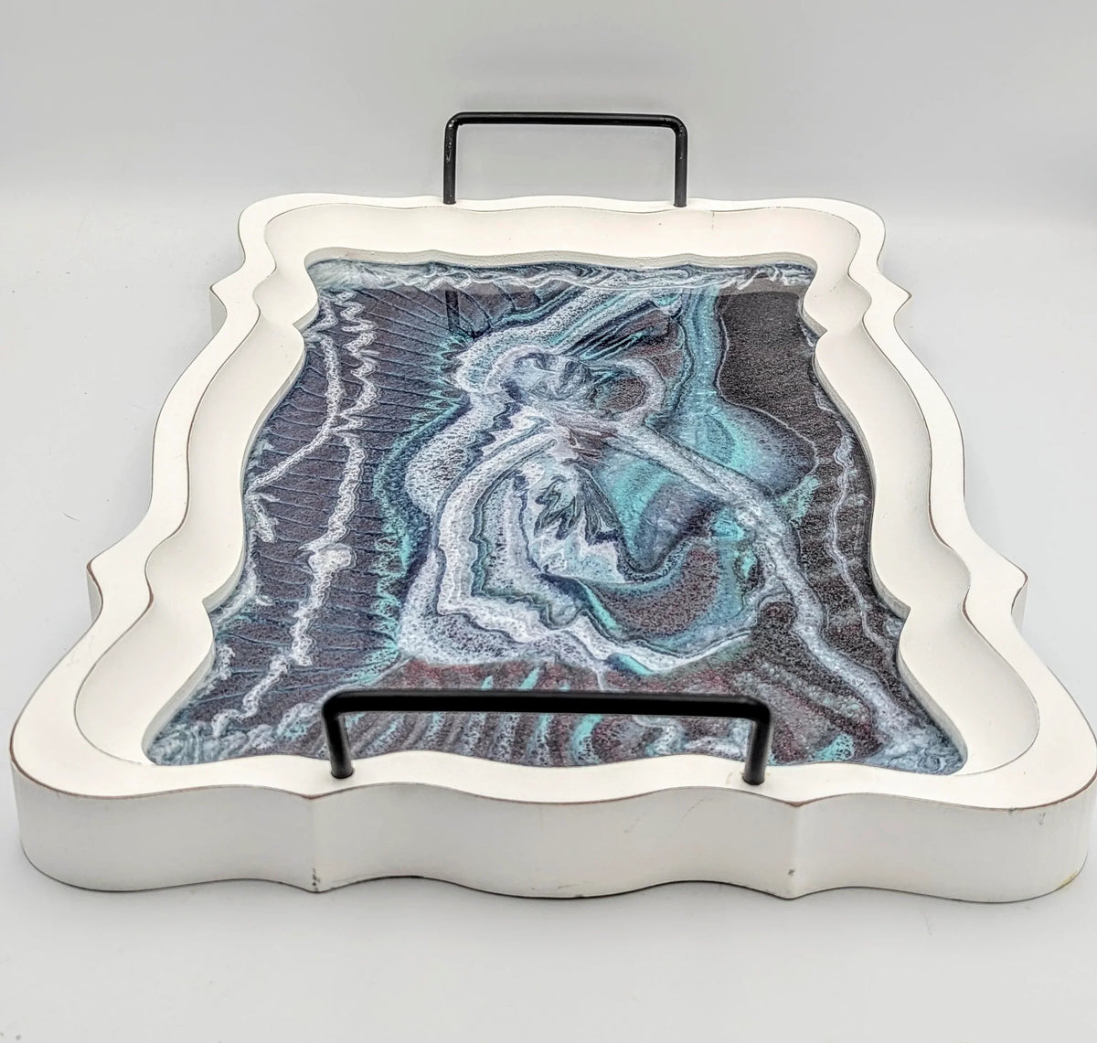 Decorative serving tray with abstract resin art in blue, white, and black tones, curved edges