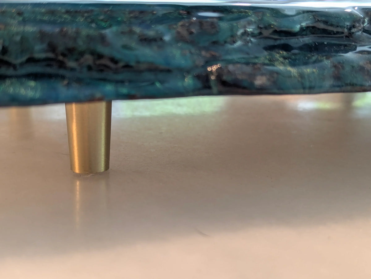 Close-up of a blue resin tray with gold metal leg on a light surface