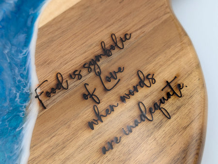 Wooden cutting board with ocean resin design and engraved quote about food and love