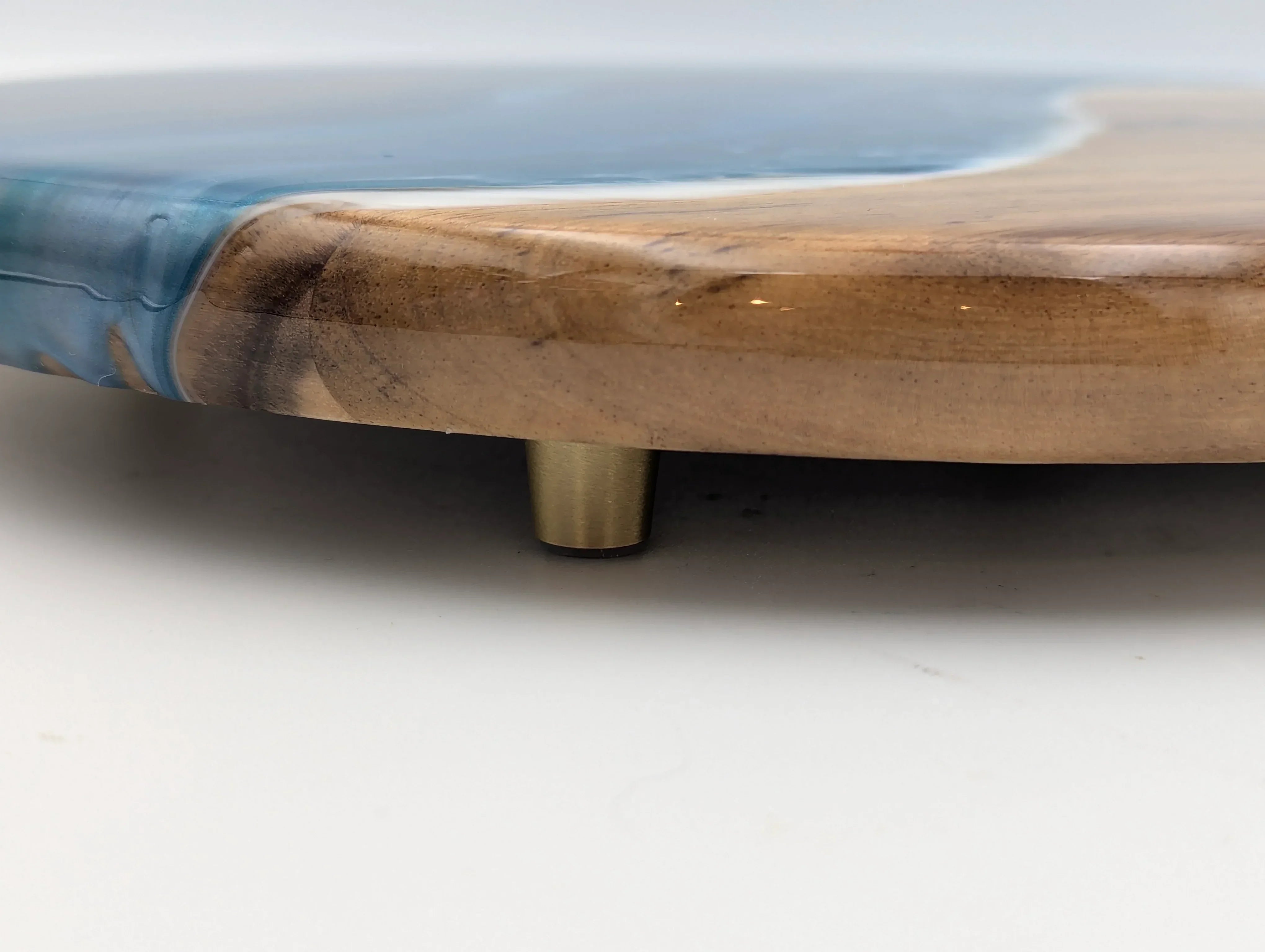 Close-up of wood and blue resin serving tray with gold metal feet on white background