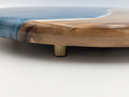 Close-up of wood and blue resin serving tray with gold metal feet on white background