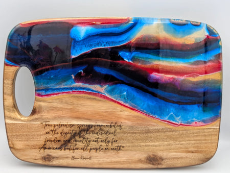 Wooden cutting board with abstract resin art in blue and red, engraved inspirational quote