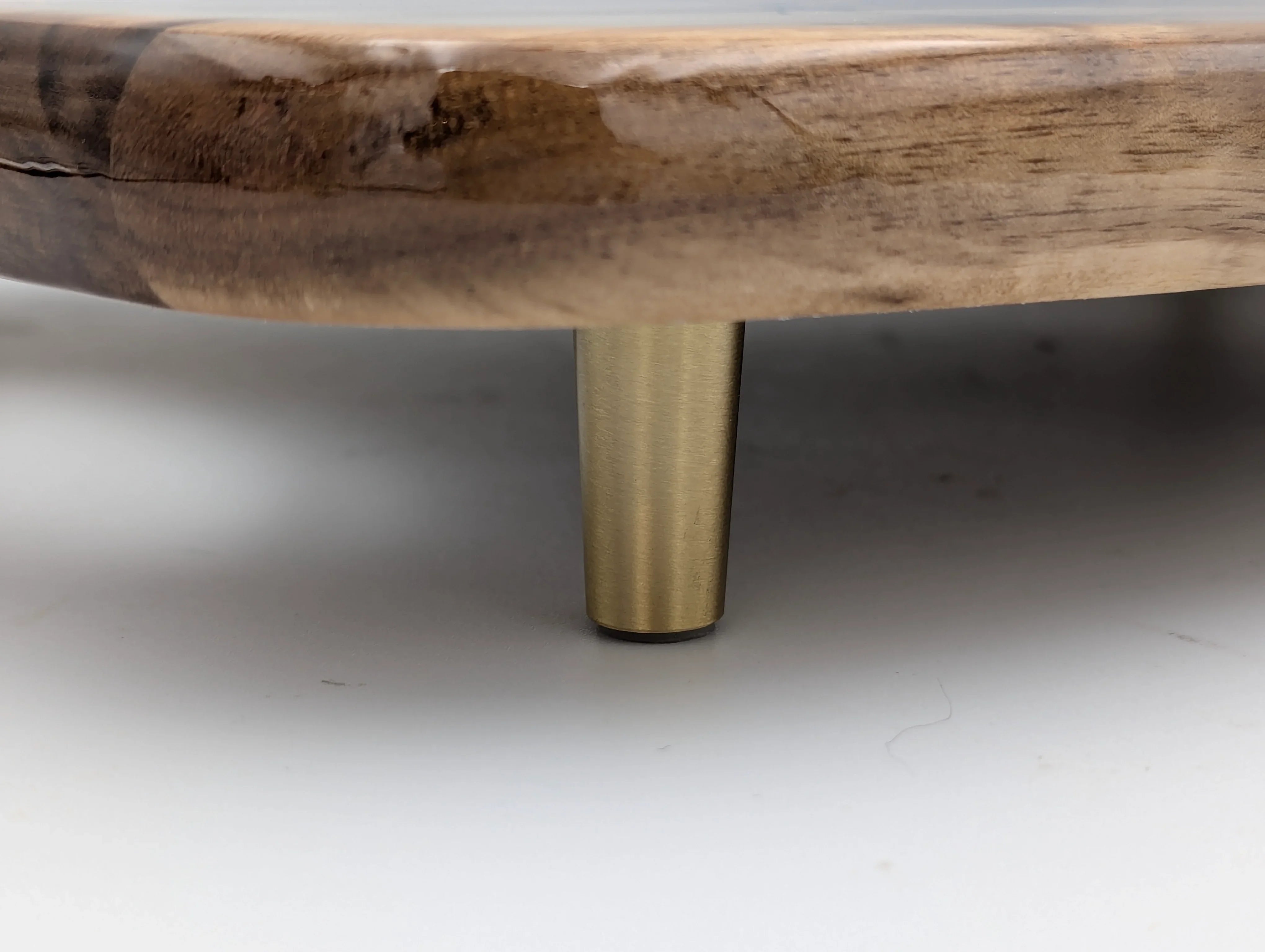 Close-up of round wood tray with brass metal leg, modern home decor detail
