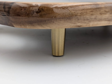 Close-up of round wood tray with brass metal leg, modern home decor detail