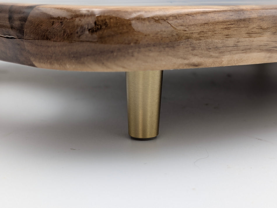 Close-up of round wood tray with brass metal leg, modern home decor detail