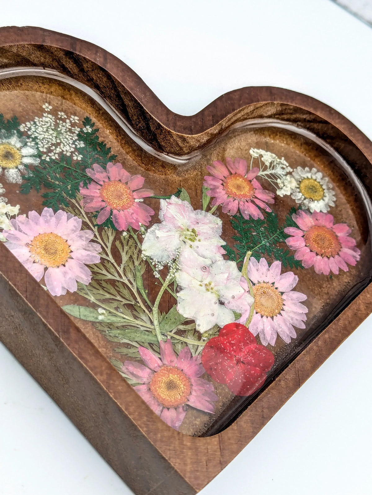 Heart-shaped wooden jewelry box with pressed dried flowers under resin lid
