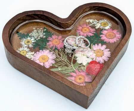 Custom engagement rings on heart-shaped wooden tray with pressed flowers