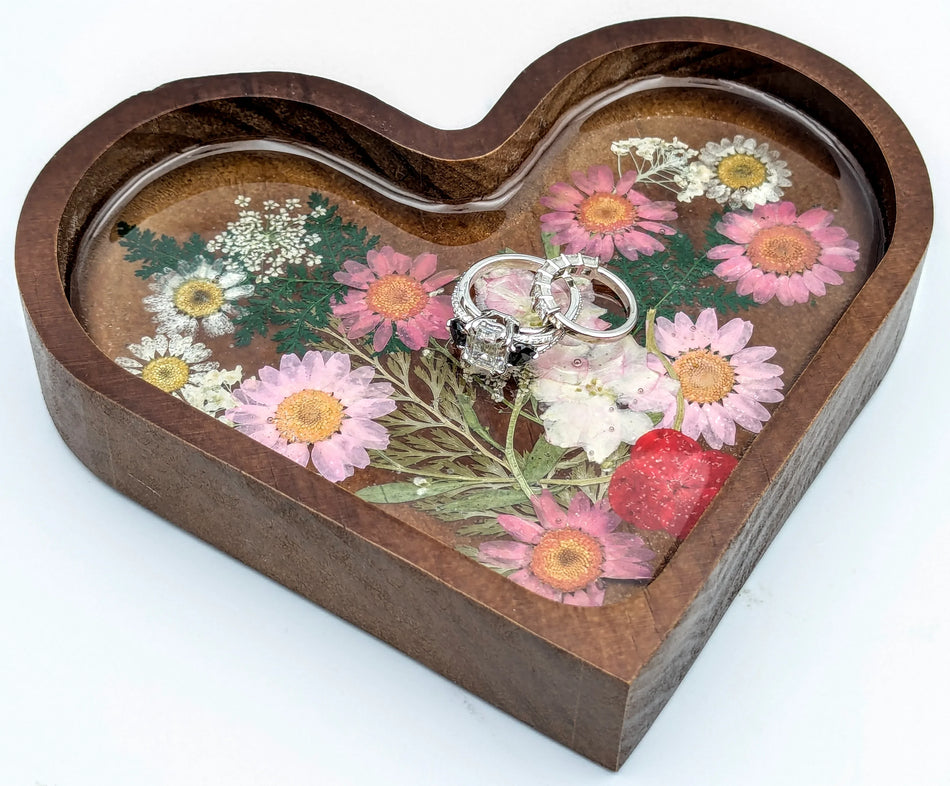 Custom engagement rings on heart-shaped wooden tray with pressed flowers