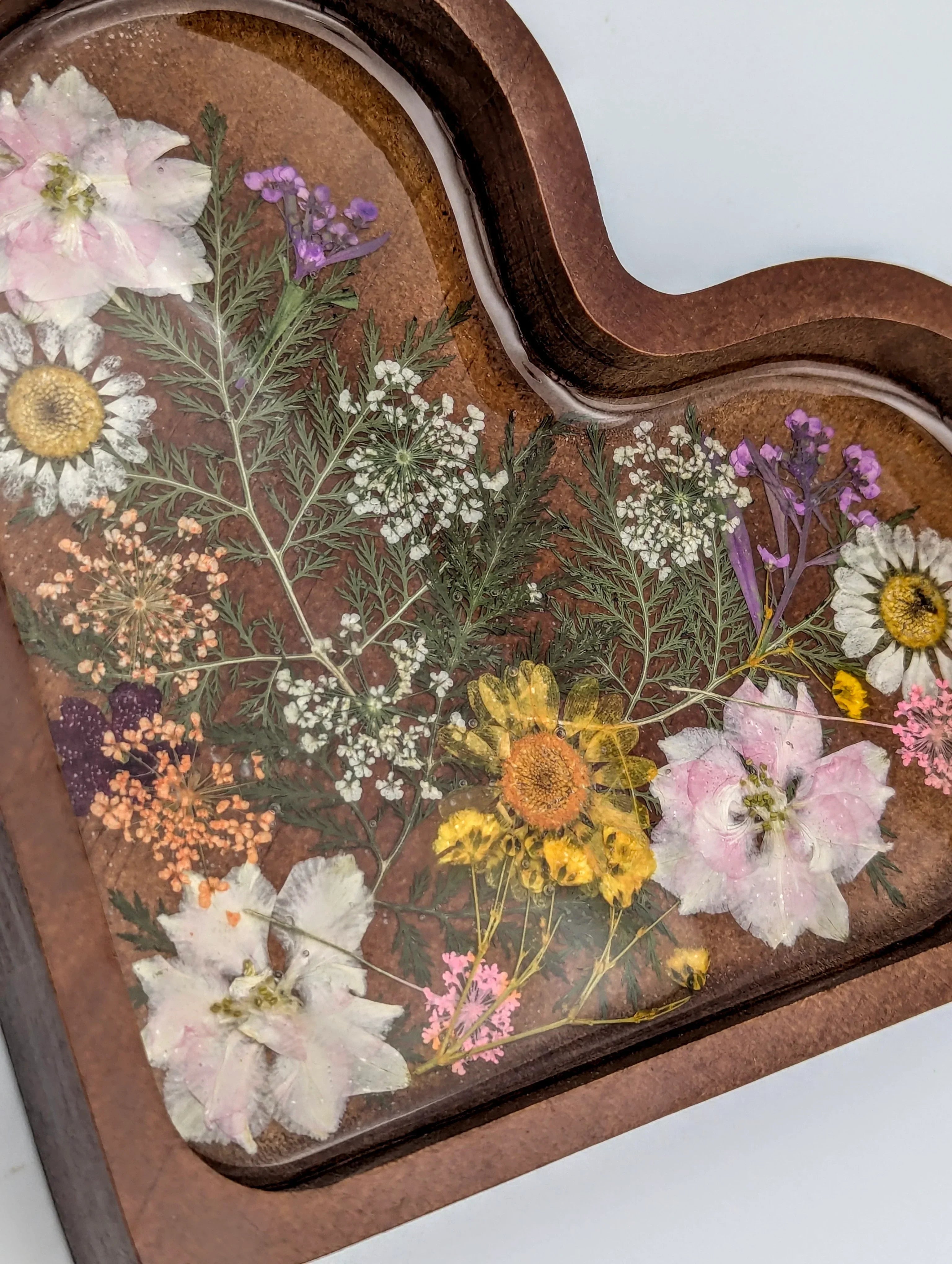 Heart-shaped wooden tray with assorted pressed flowers in clear resin