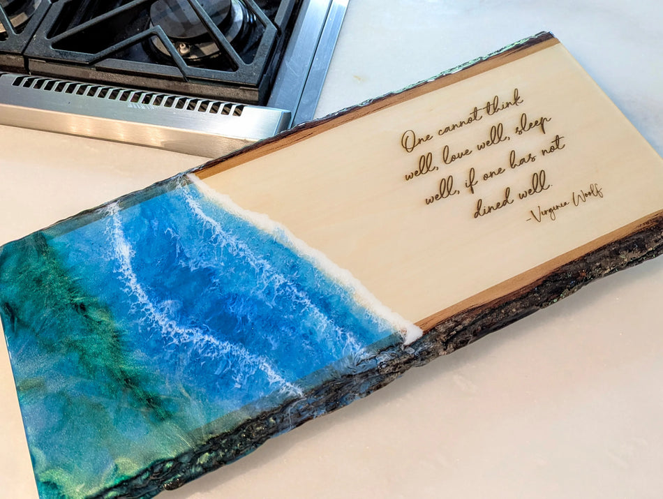 Resin ocean art wooden cutting board with engraved Virginia Woolf dining quote on kitchen counter