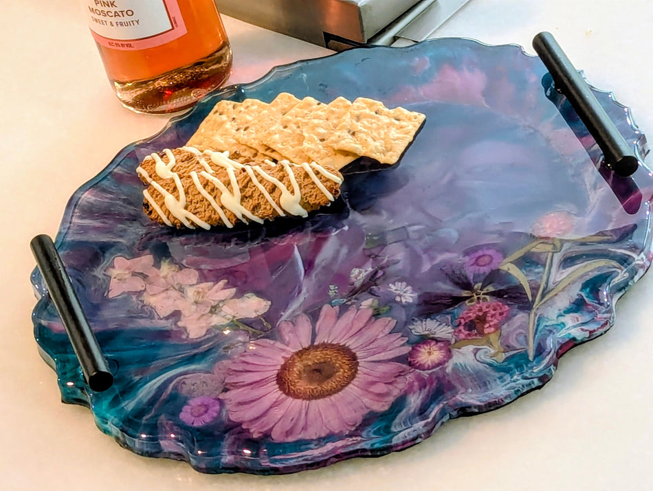 Epoxy resin serving tray with floral design, holding crackers and a bottle of pink moscato wine.
