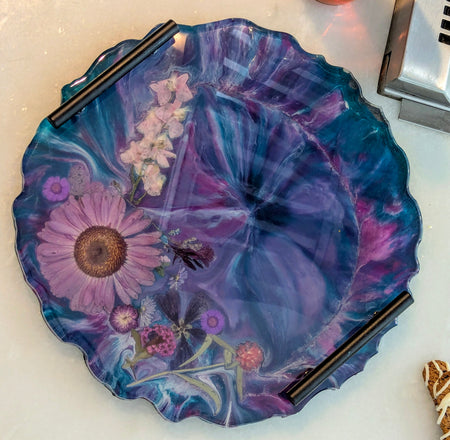 Handcrafted resin tray with pressed flowers, purple and blue swirls, scalloped edge, and black handles