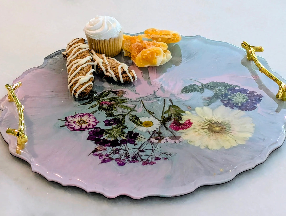 Elegant floral serving tray with gold handles, holding cupcakes, biscotti, and dried fruit for a chic dessert presentation.