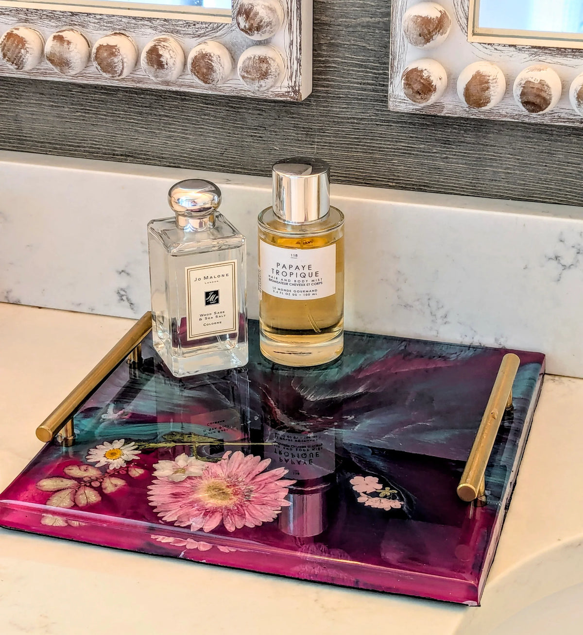 Epoxy resin tray with dried flowers, holding perfume bottles on marble vanity, decorative home accessory