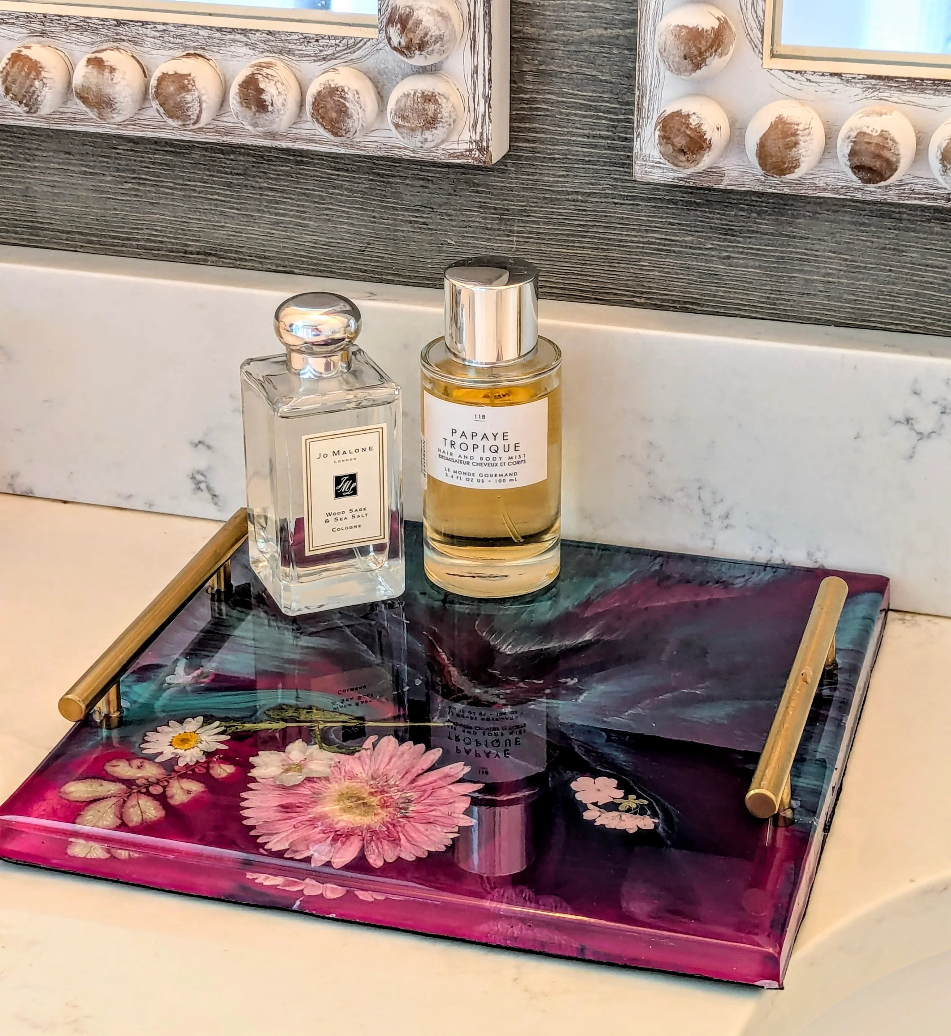Epoxy resin tray with dried flowers, holding perfume bottles on marble vanity, decorative home accessory