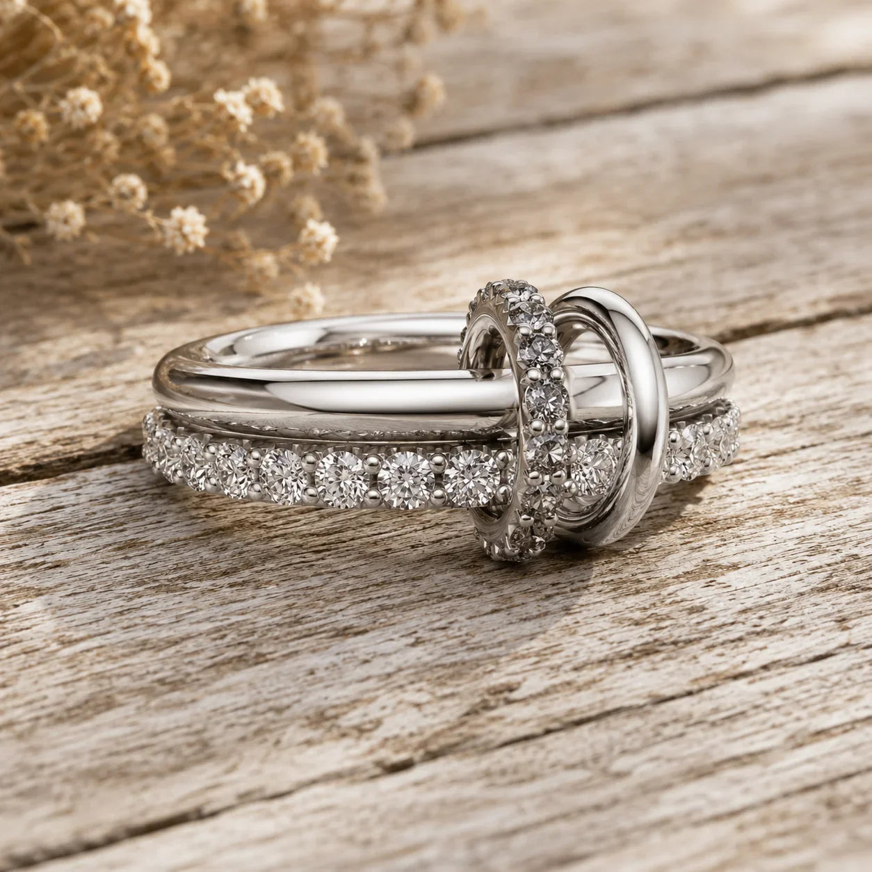 Elegant diamond engagement ring set with pave band, displayed on rustic wood with dried flowers