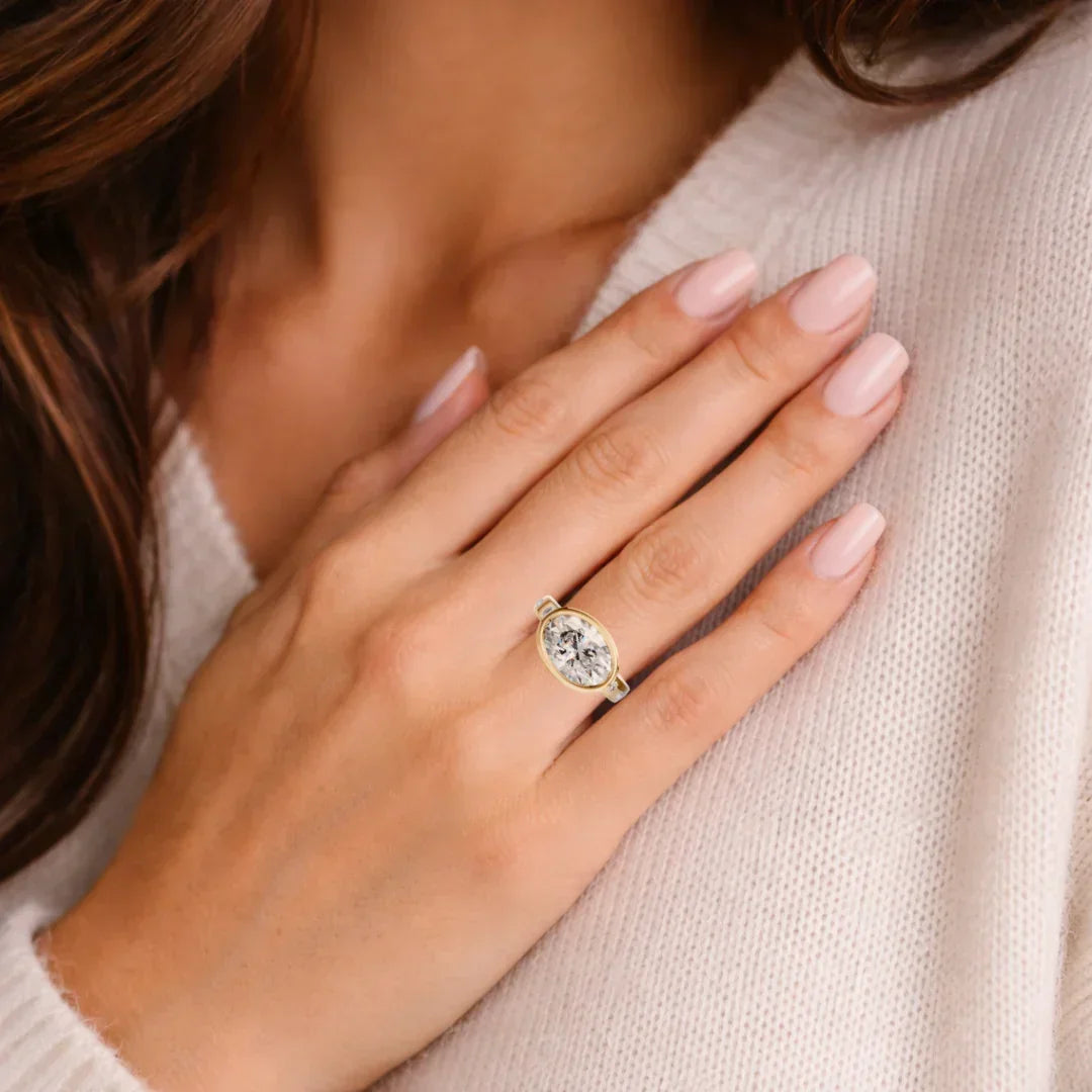 Oval solitaire diamond engagement ring with gold band on woman's hand