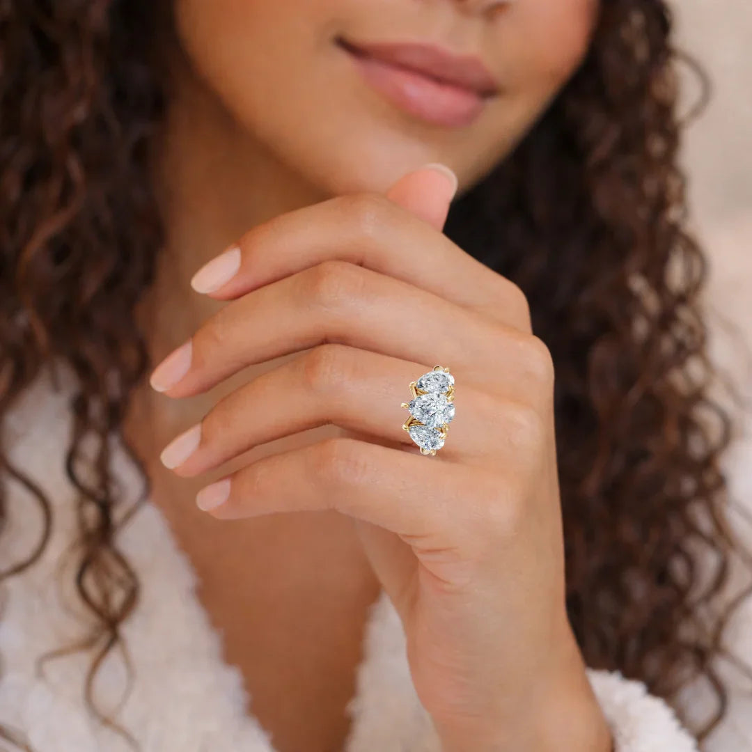 Woman wearing a gold custom engagement ring with three large oval diamonds on her finger