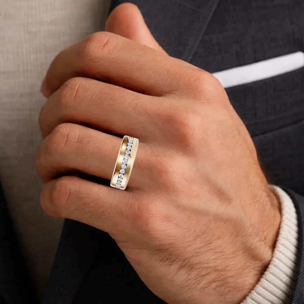 Close-up of a man's hand wearing a gold band ring with a row of inset diamonds.