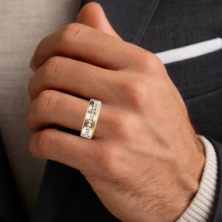 Close-up of a man's hand wearing a gold band ring with a row of inset diamonds.