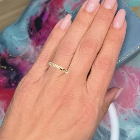 Close-up of a hand wearing a delicate twisted gold band ring.