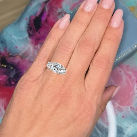 Close-up of a woman's hand wearing a custom three-stone diamond engagement ring.