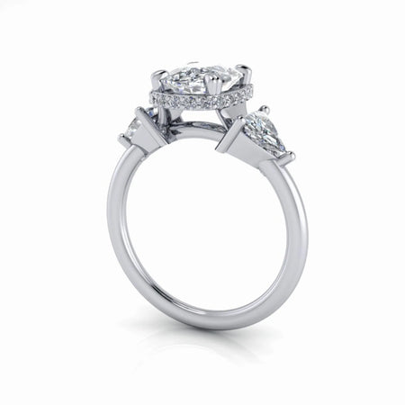 Side view of a custom diamond engagement ring with three stones and pavé halo setting