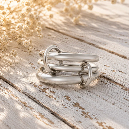 Modern silver link ring stack on rustic wood with dried flowers, custom jewelry design