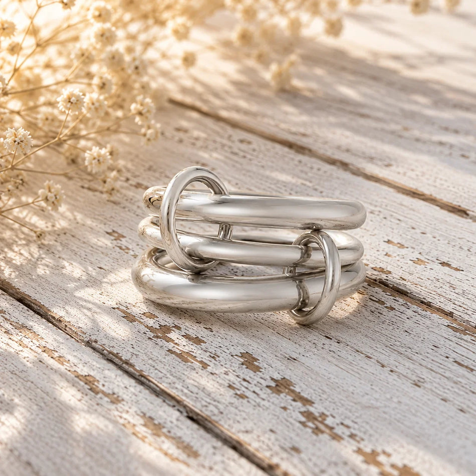 Modern silver link ring stack on rustic wood with dried flowers, custom jewelry design