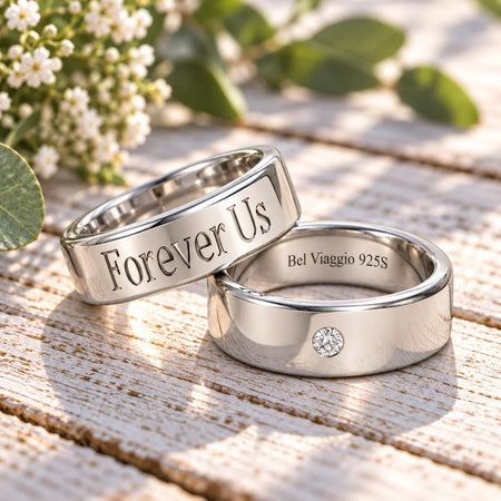 Two custom silver wedding bands, one engraved with 'Forever Us' and one featuring a small diamond.