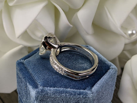 Cushion cut moissanite engagement ring by Bel Viaggio Designs on a blue velvet box