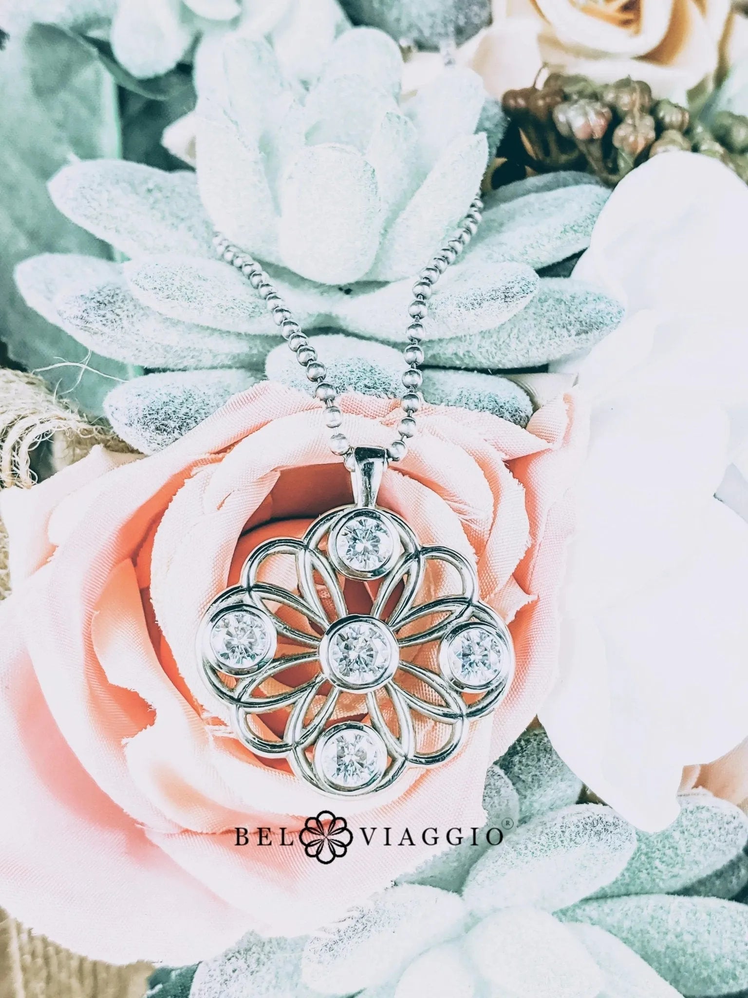 Floral diamond pendant necklace with silver chain displayed on pastel artificial flowers